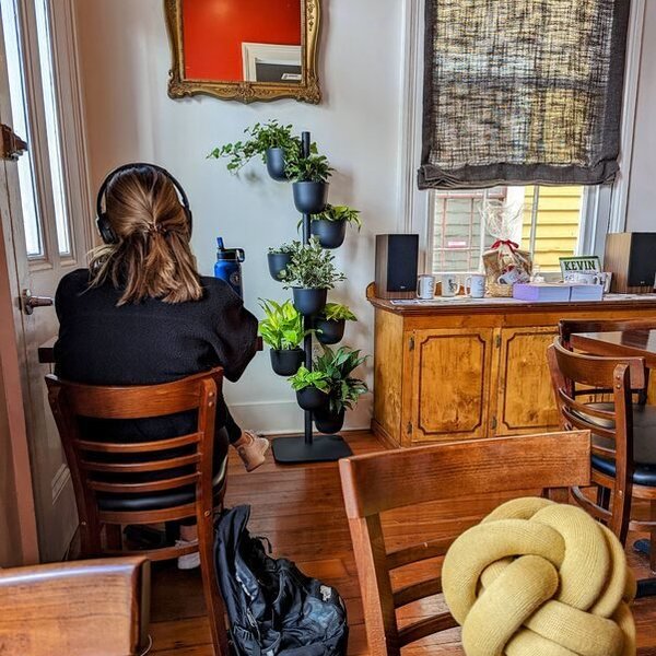 A student in headphones working at a table inside the Magazine Street shop, backpack on the wood floor beside her